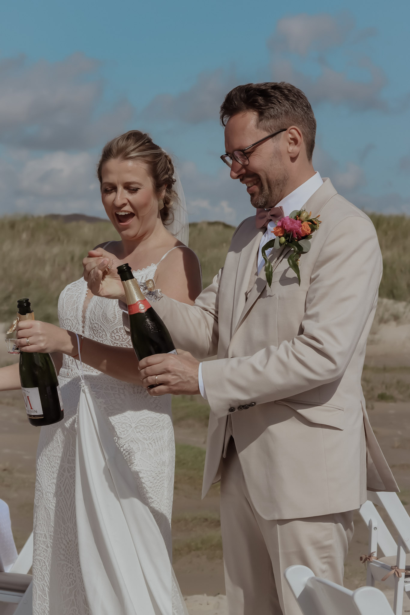 Bride and groom opening champagne and celebrating after their wedding in Denmark in a natural outdoor setting.