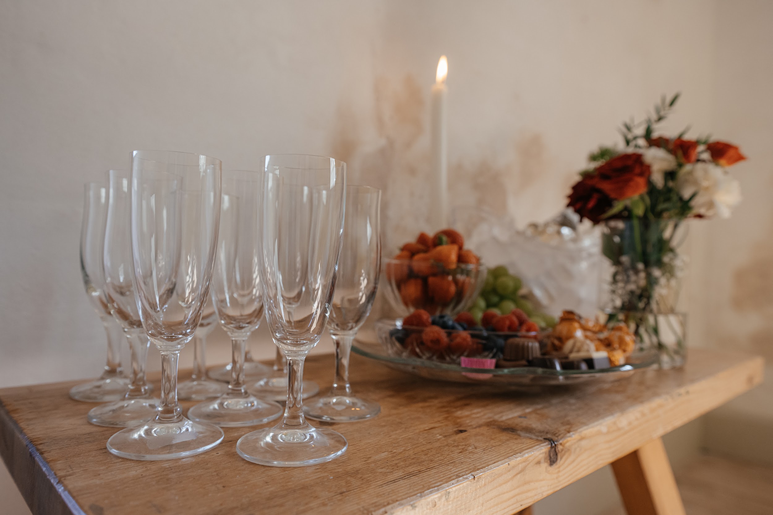 Table set with champagne glasses, fresh fruit, and flowers, ready for a wedding celebration.