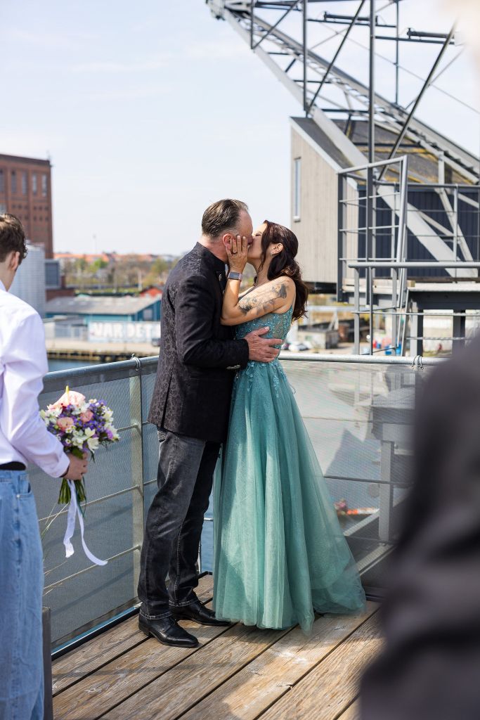 Bride and groom kissing on a rooftop terrace after their wedding in Denmark, overlooking the city and waterfront.