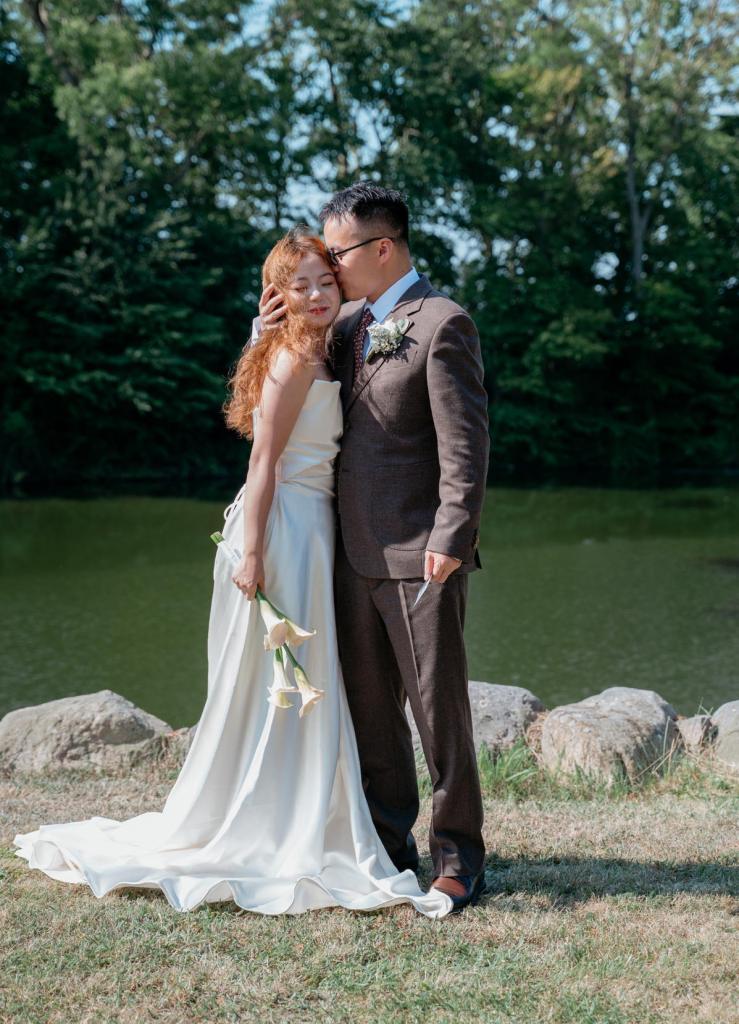 Newly married couple sharing a tender moment beside a lake after their wedding ceremony in Denmark.