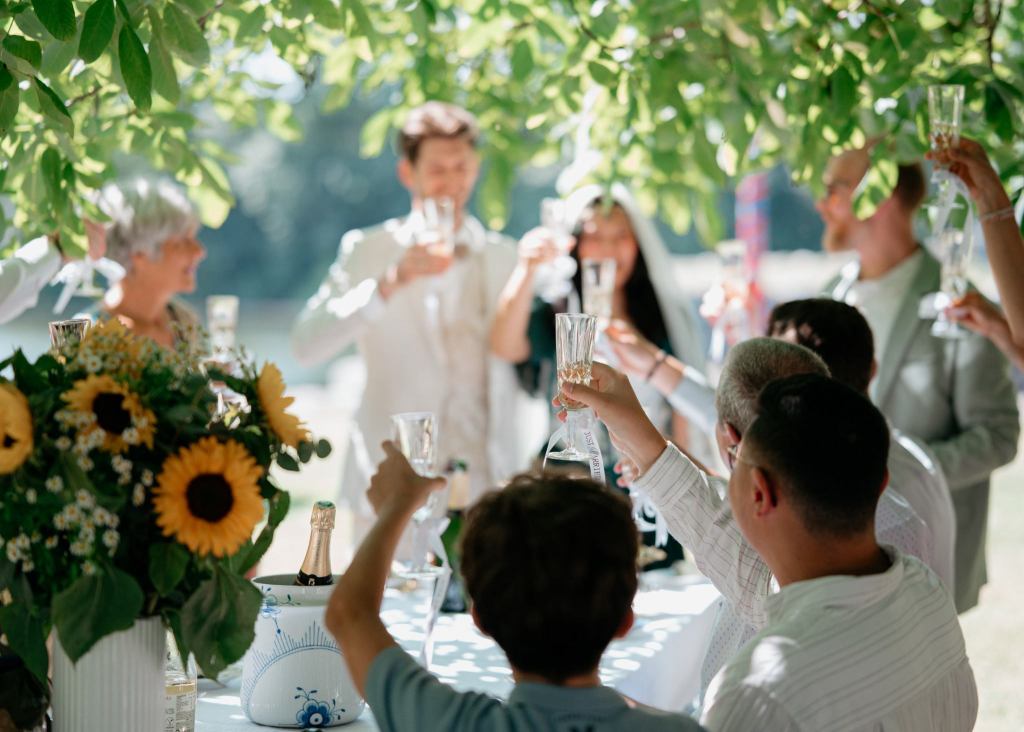 Wedding couple and guests raising champagne glasses during an outdoor wedding celebration in Denmark.