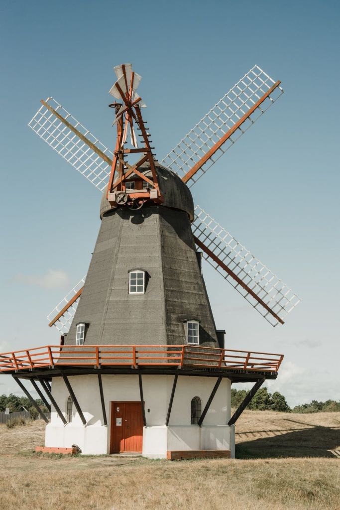 Historic Danish windmill surrounded by open countryside under a clear blue sky.